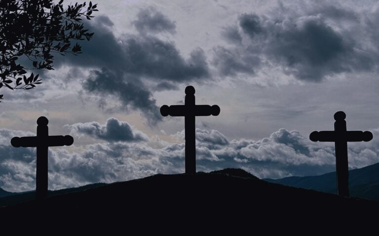 Three crosses silhouetted on a hill under a cloudy sky